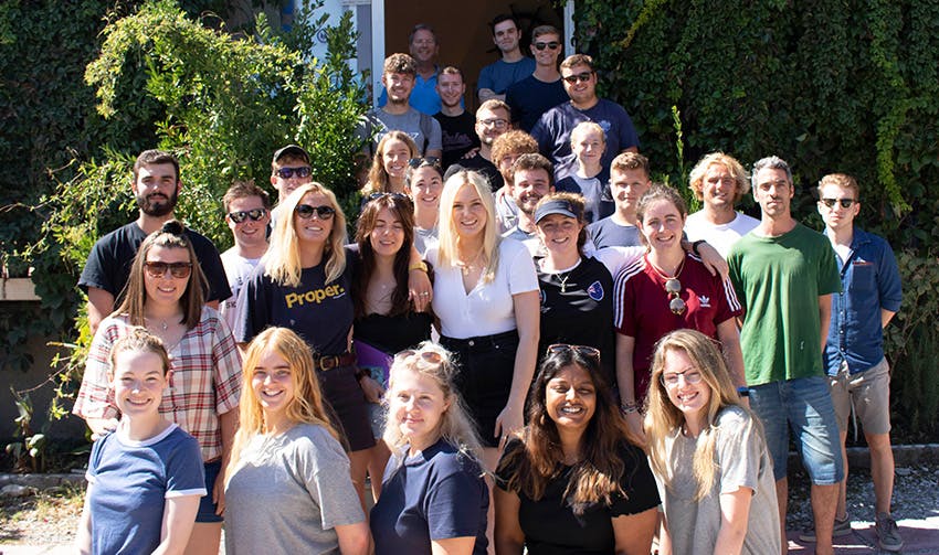 Large group of interns and team members gathered outside in the sun, smiling and posing during their summer internship experience.